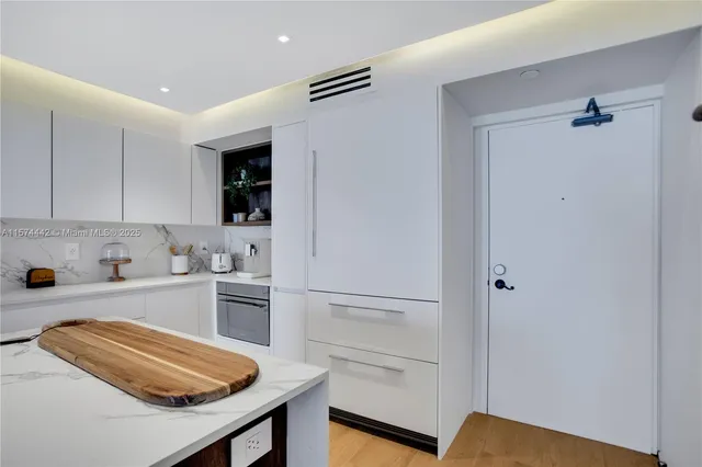 a kitchen with a refrigerator and white cabinets