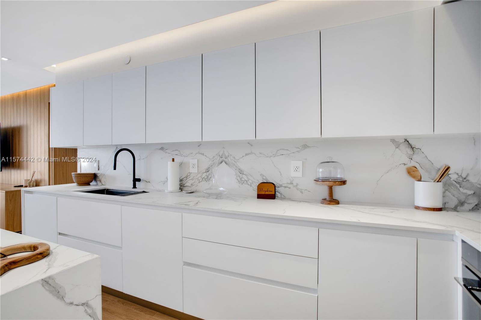 9195 Collins Avenue, Unit 903 Surfside, FL 33154 - Photo 13 of 51 a kitchen with sink and white cabinets