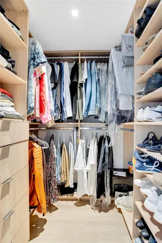 a view of walk in closet with clothes and shoes