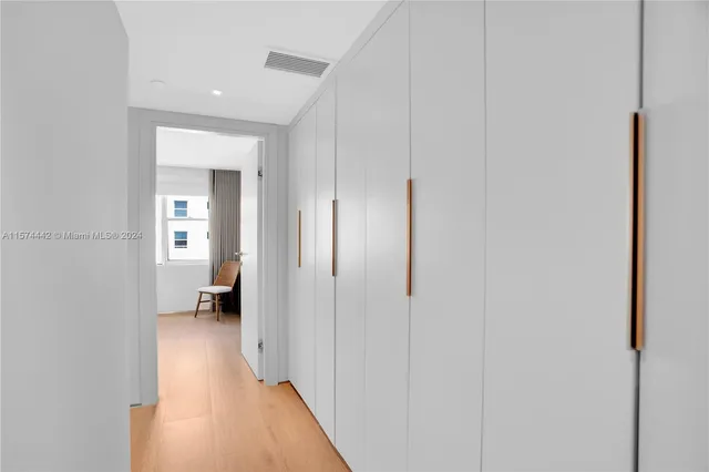 a view of a hallway with a view of bedroom and chair