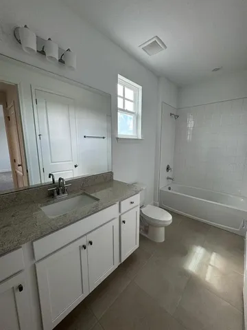 a bathroom with a granite countertop sink a toilet and a mirror