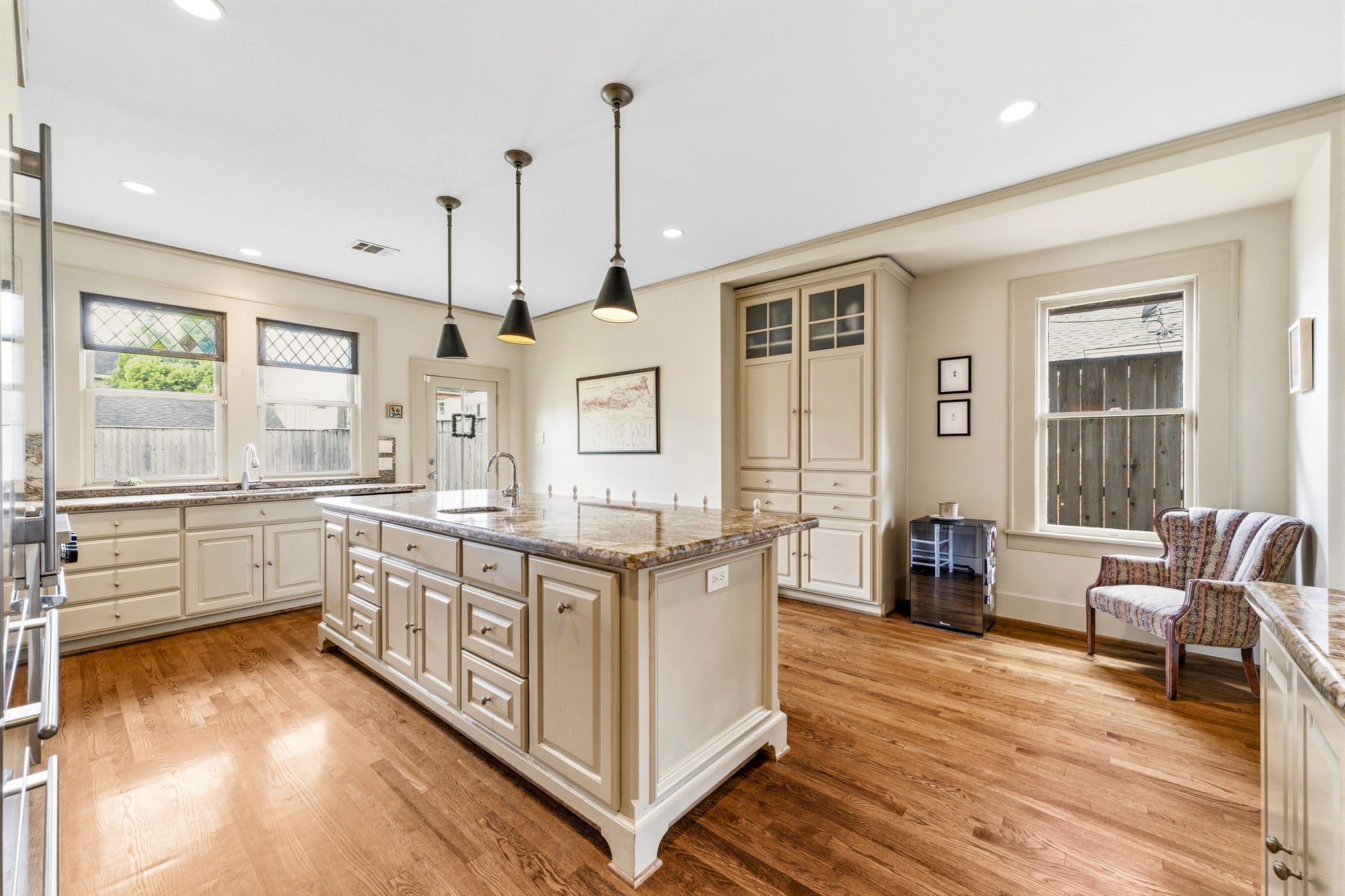 1521 Kipling Street Houston, TX 77006 - Photo 17 of 35 This spacious kitchen features hardwood floors, ample natural light, and an elegant island with granite countertops. The room includes modern appliances, stylish pendant lighting, and plenty of cabinet space for storage.