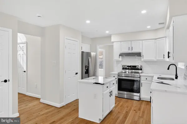 a kitchen with stainless steel appliances granite countertop a refrigerator a stove and a sink