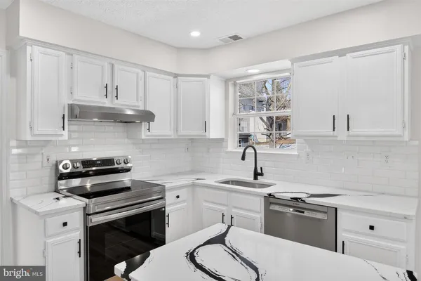 a kitchen with stainless steel appliances a sink stove and cabinets