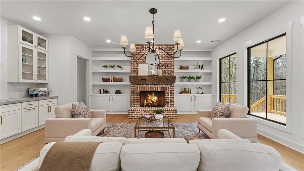 165 Highlands Chase Ball Ground, GA 30107 - Photo 7 of 40 a living room with furniture a fireplace and a chandelier
