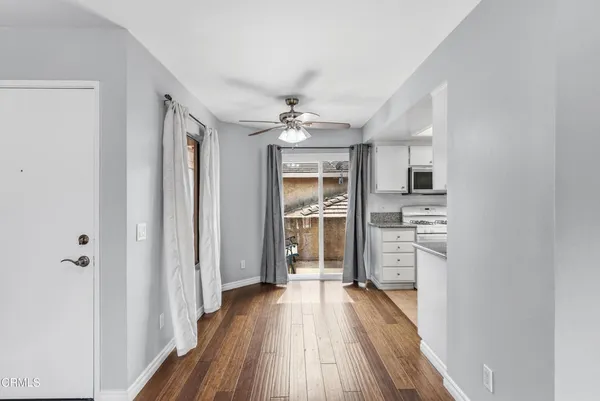 a view of a hallway with wooden floor and a kitchen