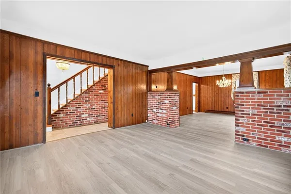 a view of an empty room with wooden floor and stairs