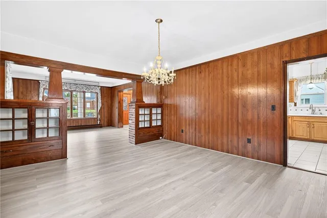 a view of an empty room with wooden floor and a kitchen
