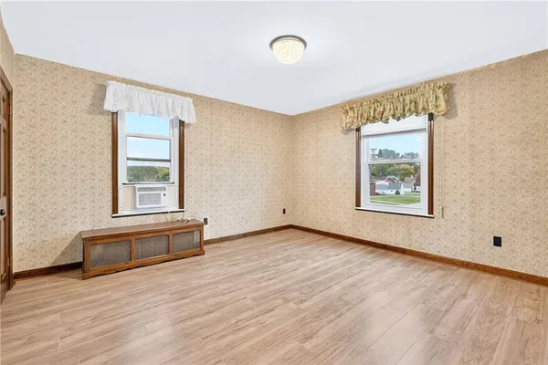 a view of an empty room with a window and wooden floor