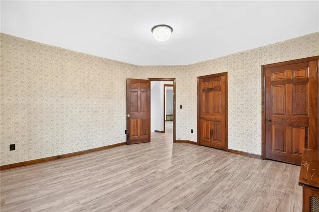 a view of an empty room with wooden floor and closet