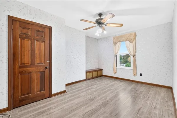 an empty room with wooden floor fan and windows