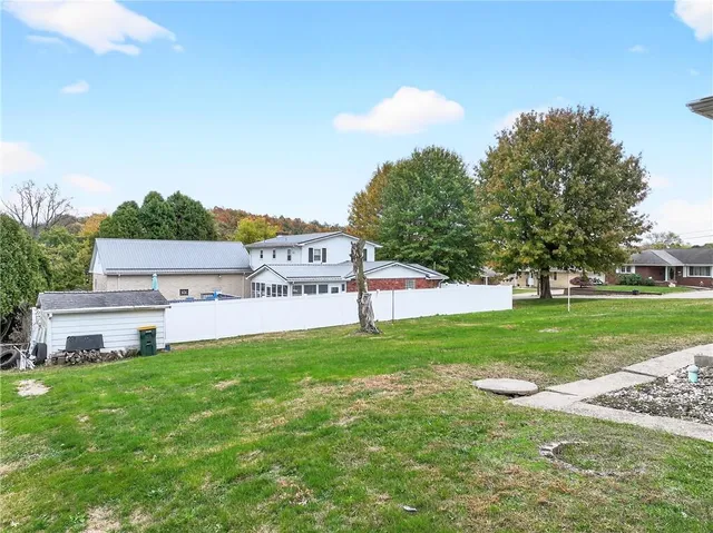 a view of a house with a big yard and large trees