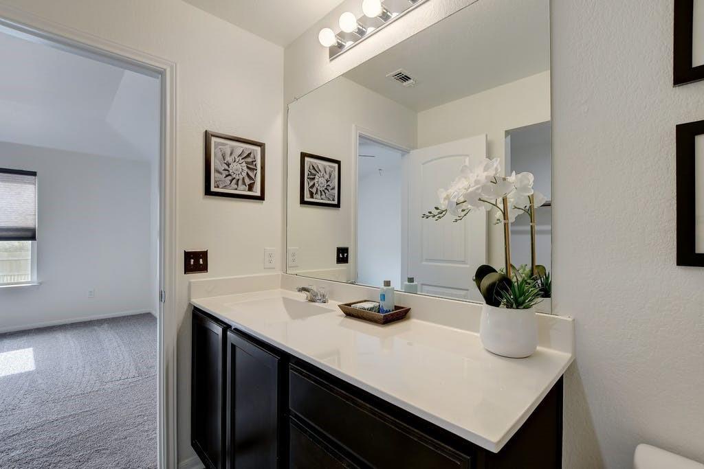173 Rafe Court Kyle, TX 78640 - Photo 15 of 27 Half bathroom with vanity, light colored carpet, and a textured wall