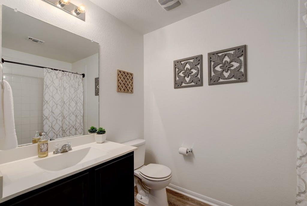 173 Rafe Court Kyle, TX 78640 - Photo 19 of 27 Full bathroom featuring curtained shower, vanity, and light wood-style floors
