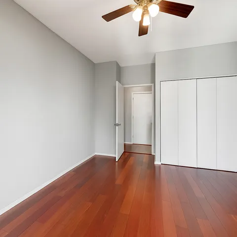 an empty room with wooden floor chandelier fan and closet area