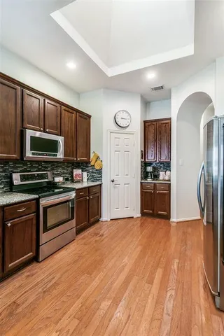 a kitchen with stainless steel appliances wooden floor sink and wooden cabinets