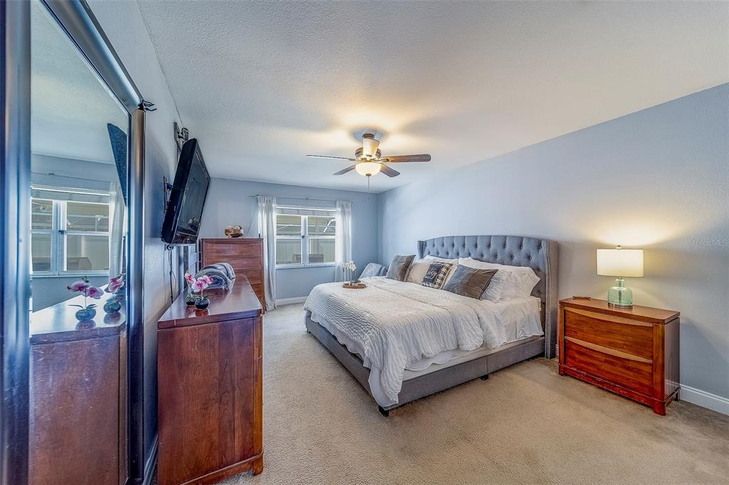 14414 91st Avenue North Seminole, FL 33776 - Photo 17 of 58 a spacious bedroom with a bed and a chandelier