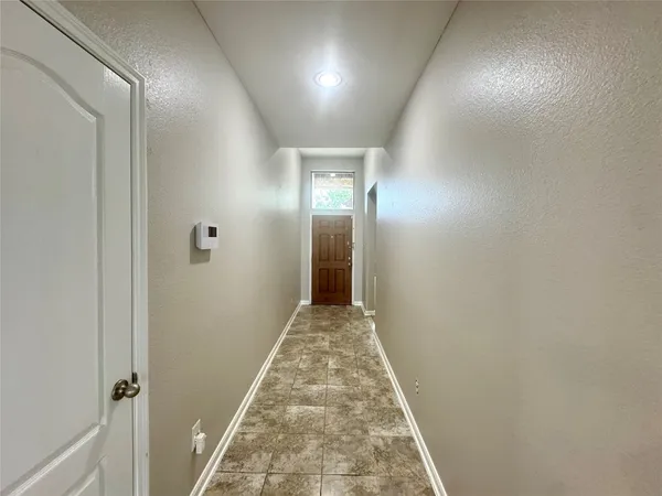 a view of a hallway with wooden floor and a bathroom