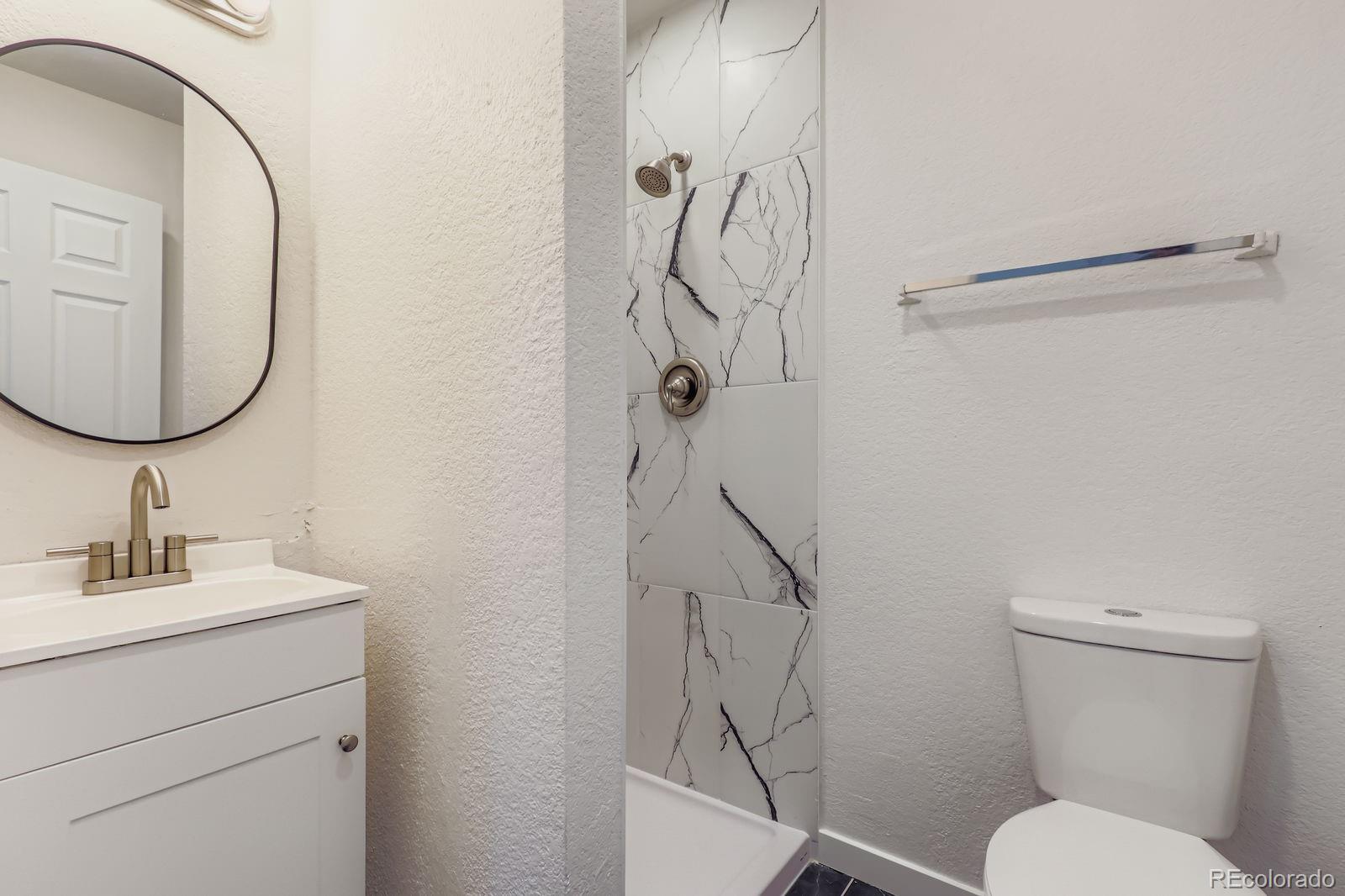 831 Sable Boulevard Aurora, CO 80011 - Photo 15 of 26 a bathroom with a toilet sink and mirror