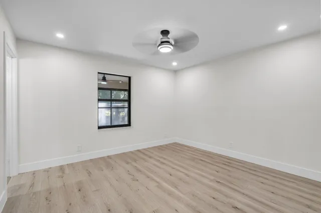 an empty room with wooden floor and windows