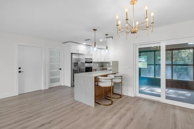 a kitchen with stainless steel appliances granite countertop a refrigerator a sink a stove and white cabinets