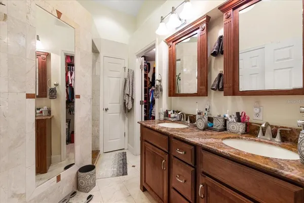 a bathroom with a granite countertop double vanity sink mirror and shower