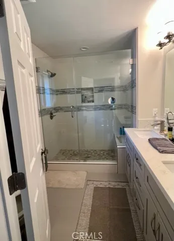 a bathroom with a granite countertop sink a mirror and shower