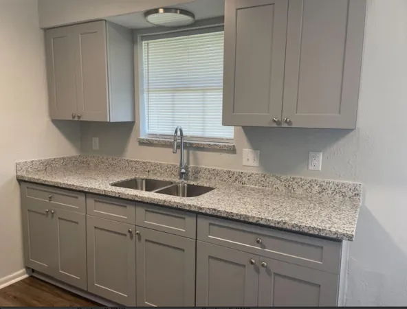 a kitchen with granite countertop white cabinets and refrigerator