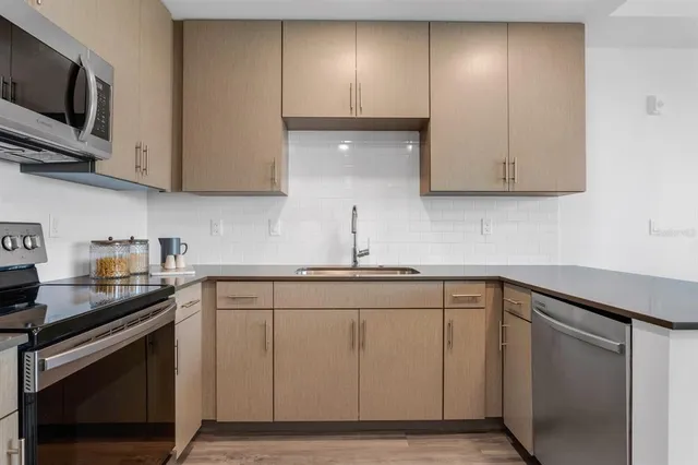 a kitchen with stainless steel appliances granite countertop white cabinets a stove a microwave and a sink