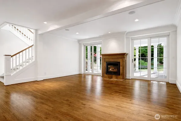 a view of an empty room with wooden floor fireplace and a window