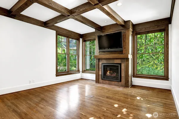 a view of an empty room with wooden floor fireplace and a window