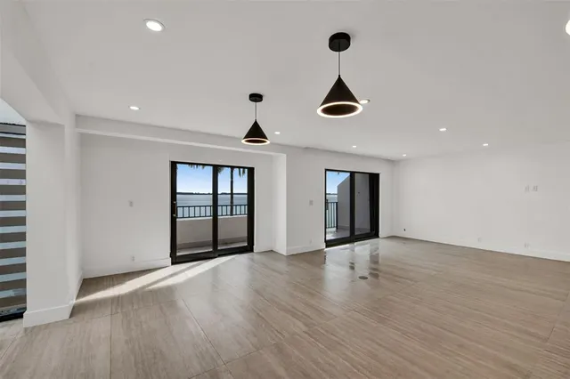an empty room with wooden floor cabinet and windows
