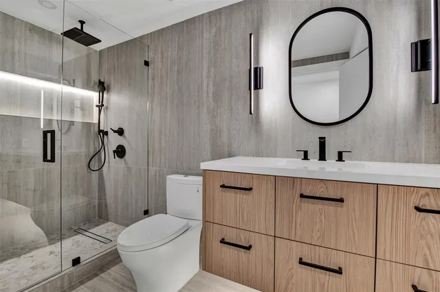 a bathroom with a toilet sink vanity granite and shower