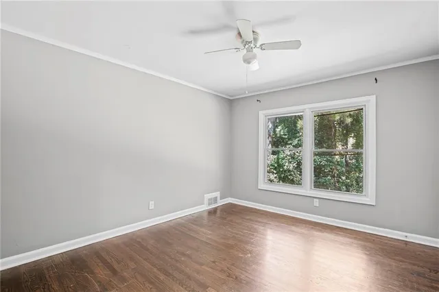 an empty room with wooden floor fan and windows