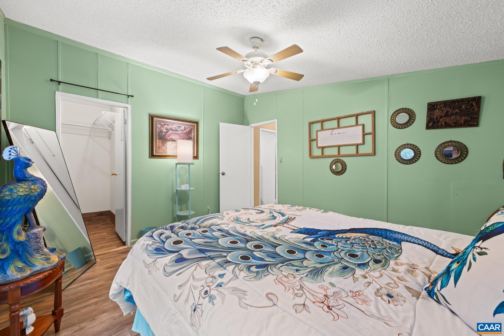 61 Snapdragon Road Ruckersville, VA 22968 - Photo 21 of 47 Vibrant and stylish bedroom featuring soothing sage green walls, rich wood-look flooring, and a breezy ceiling fan. Complete with a full walk-in closet and generous natural light, this cozy sanctuary is the perfect place to rest and unwind!