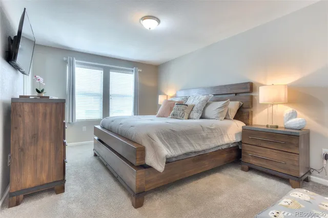 a bed sitting in a bedroom next to a window with a flat screen tv