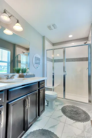 a spacious bathroom with a granite countertop sink a toilet a mirror and shower