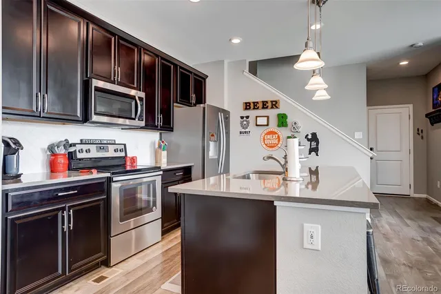 a kitchen with stainless steel appliances granite countertop a refrigerator a stove top oven a sink and dishwasher