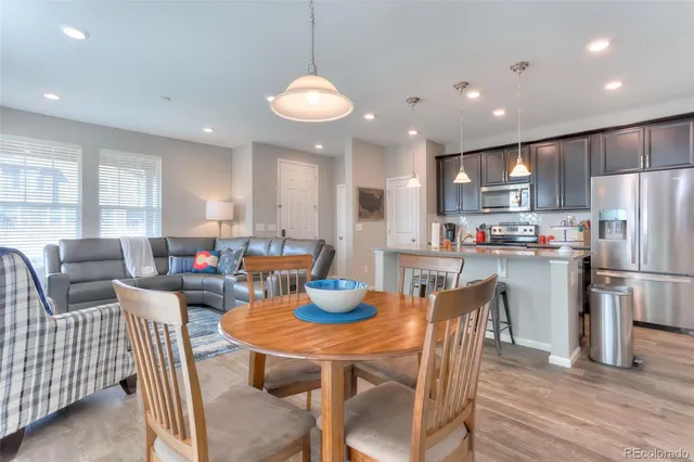a kitchen with stainless steel appliances granite countertop a dining table chairs refrigerator sink and cabinets