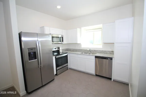 a kitchen with granite countertop stainless steel appliances a sink and a window