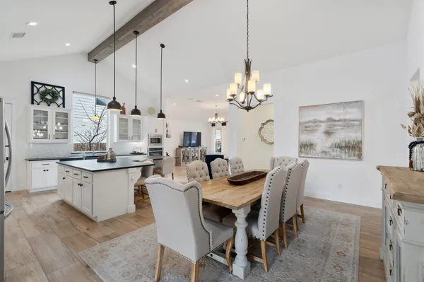 a dining room filled chandelier and kitchen view