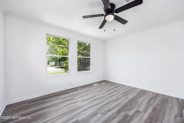 an empty room with a window and a ceiling fan