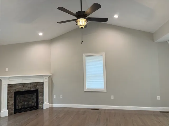 an empty room with ceiling fan and a fireplace