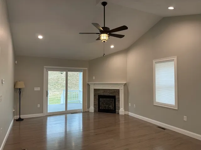 an empty room with wooden floor a ceiling fan and windows