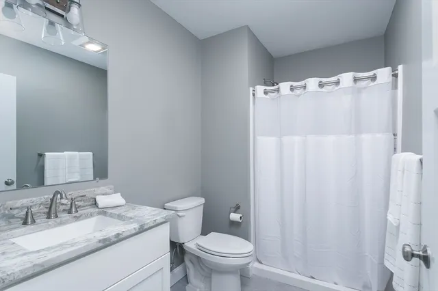 a bathroom with a granite countertop sink toilet and a mirror