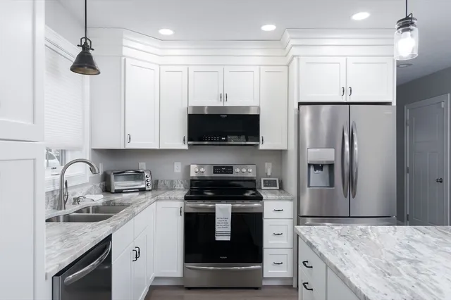 a kitchen with a sink stainless steel appliances and white cabinets