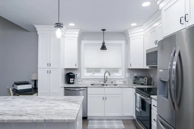 a kitchen with stainless steel appliances kitchen island granite countertop a sink refrigerator and cabinets