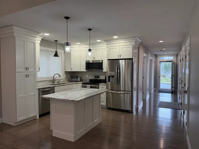 a large kitchen with stainless steel appliances granite countertop a refrigerator and a stove top oven