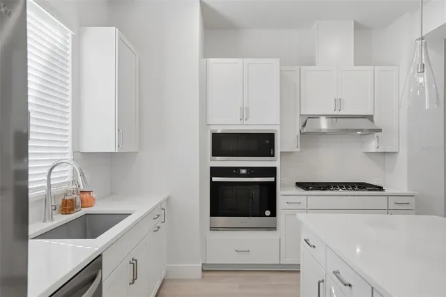 a kitchen with white cabinets and stainless steel appliances