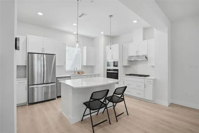 a kitchen with kitchen island white cabinets and stainless steel appliances